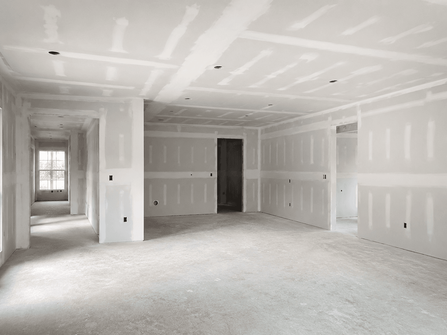 Drywall installation and finish prep in a bright interior room
